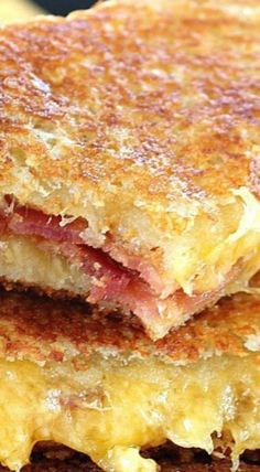 two grilled cheese sandwiches stacked on top of each other with bacon and melted cheese