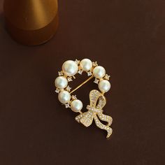 Indulge in the ultimate sophistication with our Copper Round Pearl Bow Brooch. Made with luxurious copper and adorned with a delicate round pearl, this brooch adds a touch of elegance to any outfit. The intricate bow design evokes a sense of timeless beauty, making it the perfect accessory for any occasion. Elevate your style with this exclusive piece.      Tarnish proof    Water proof    Sleep / Nap proof    Safe for sensitive skin    Wear it while working out &showering    Designed to wear 24/ Elegant Anniversary Brooch With Bow, Elegant Brooches With Decorative Bow For Anniversary, Elegant Round Brooch For Anniversary, Gold Wedding Brooches Chic Style, Gold Wedding Brooches In Chic Style, Elegant Round Brooches For Anniversary, Elegant Anniversary Brooch With Decorative Bow, Chic Gold Wedding Brooch, Gold Chic Wedding Brooches