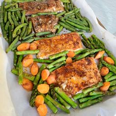 some fish and asparagus are on a white plate with carrots in it