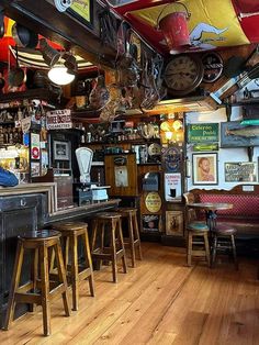 the inside of a bar with lots of stools and clocks on the wall above it