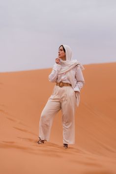 a woman standing in the desert with her hand on her chin and looking off into the distance