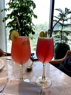 two cocktails sitting on top of a table next to each other in front of a window