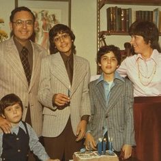 a group of people standing next to each other in front of a table with a cake on it