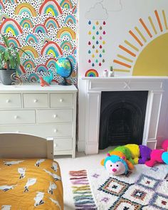 a child's bedroom with colorful wallpaper and toys on the floor in front of a fireplace