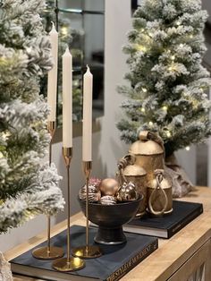 candles and ornaments on a table in front of a christmas tree