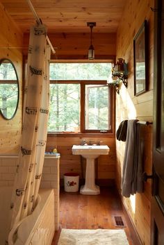 a bathroom with wooden walls and flooring in the middle, along with a shower curtain