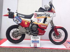 a red and white dirt bike on display in front of a sign that says yamaha