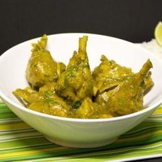 a white bowl filled with green food next to a plate of rice and lime wedges