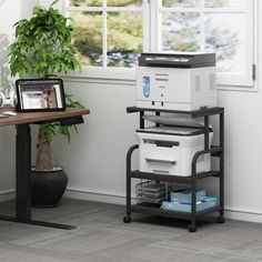 a printer sitting on top of a table next to a potted plant in front of a window