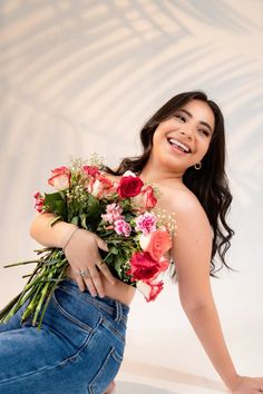 a woman is holding flowers and smiling for the camera