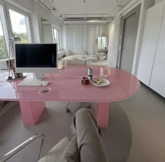 a living room with a pink table in the middle and a tv on top of it