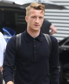 a man in black shirt and backpack walking down street with his hand on his hip