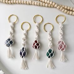 four key chains with tassels on them sitting on a plate next to beads