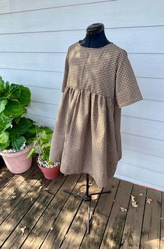 This babydoll-style dress is perfect for everyday, casual wear. The design comprises a short bodice with half-length sleeves and a gathered skirt with in-seam pockets. Sporting a midi length and no closure method, this dress is comfortable and stylish. These are made with 100% handspun cotton in brown and black Gingham. Short Sleeve Smocked Cotton Mini Dress, Cotton Smocked Mini Dress With Short Sleeves, Cotton Smock Mini Dress With Short Sleeves, Casual Short Sleeve Smocked Mini Dress, Short Sleeve Mini Dress With Pleated Waist, Brown Short Sleeve Mini Dress For Daywear, Brown Mini Dress With Short Sleeves For Daywear, Cotton Short Sleeve Dress With Pleated Waist, Fall Smock Dress With Short Sleeves