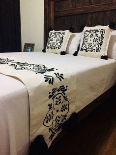 a bed with white sheets and black trimmings on it, in a bedroom