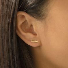 a close up of a woman's ear with a gold bar in the middle