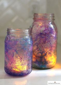 two jars filled with colored liquid sitting on top of a white table next to each other