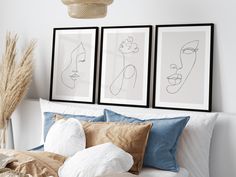 two framed art prints above a bed with pillows and blankets on top of it in a bedroom