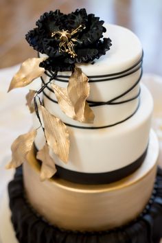 a three tiered cake with black and gold decorations