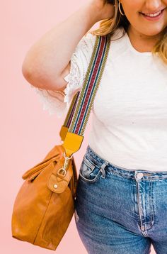 a woman in white shirt holding a brown purse and smiling at the camera with her hand on her head