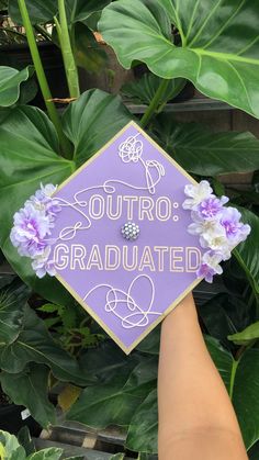 someone holding up a purple graduation cap that says, outro graduated with flowers on it