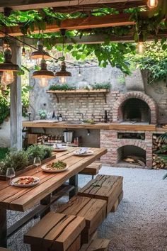 an outdoor dining area with wooden benches and lights hanging from the ceiling, surrounded by greenery