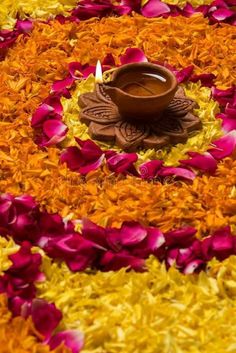 a small bowl with a candle in it surrounded by petals and petals on the ground