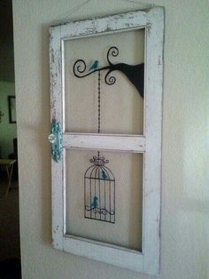 a bird in a cage is hanging on the wall next to a window with two birds inside