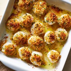 a white casserole dish filled with scallops covered in cheese and parmesan