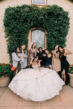 a group of women standing next to each other in front of a building with ivy growing on the wall