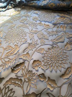 a close up view of an intricately designed bed sheet with gold flowers on it