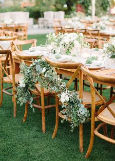 an outdoor table set up with flowers and greenery for a formal dinner or reception