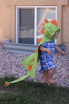 a little boy wearing a green dinosaur costume