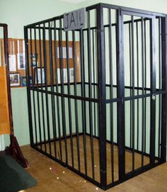 a jail cell in an empty room with wooden floors