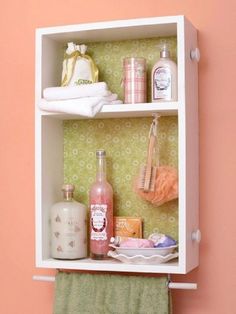 a shelf with bottles and other items on it against a pink wall in a room