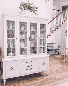 a white china cabinet with glass doors on the front and bottom, sitting in a living room