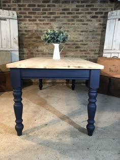 a blue table with a white vase on top and some drawers in the back ground