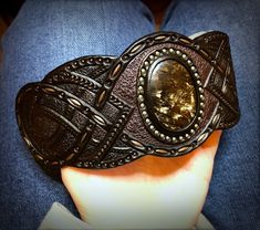 "\"Out of the dark\" is a hand tooled and hand painted leather bracelet with iridescent seraphinite cabochon. It was made to fit the 7 1/2\" (19cm) wrist. This particular cuff was MADE TO ORDER. If you would like me to design something for you welcome to place a custom order and we will discuss a design, which would match your personality. I've got plenty of different gemstones in stock, thus I believe we would find something just for you. Once the order is ready it will be shipped to you by pri Custom Handmade Leather Bracelets, Handmade Black Artisan Leather Bracelet, Handmade Artisan Black Leather Bracelet, Adjustable Hand Painted Leather Jewelry, Handmade Adjustable Cuff Bracelet, Artisan Leather Bracelet With Patina Gift, Custom Handmade Adjustable Leather Bracelet, Artisan Adjustable Black Cuff Bracelet, Handmade Adjustable Leather Bracelet