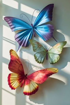 three colorful butterflies are hanging on the wall