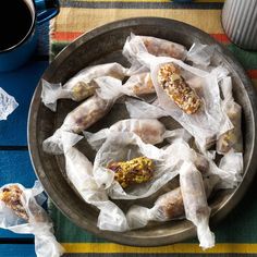 there are some food wrapped in plastic on the table next to a cup of coffee