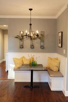 a table with two yellow pillows on it and a bench in front of the wall