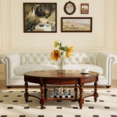 a living room with white couches and sunflowers on the coffee table in front of it