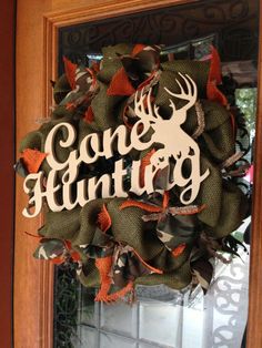 a wreath with the words gone hunting on it is hanging from a front door window