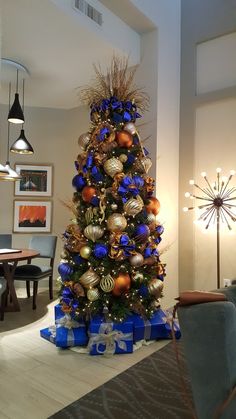 a blue and gold christmas tree in a living room with presents on the bottom floor