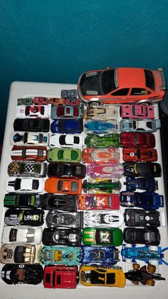 there are many different toy cars on the white table top with blue walls in the background