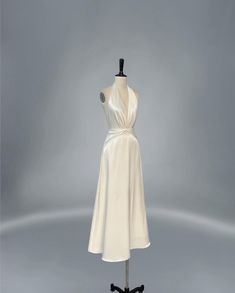 a white dress on a mannequin stand in front of a gray background with no one wearing it