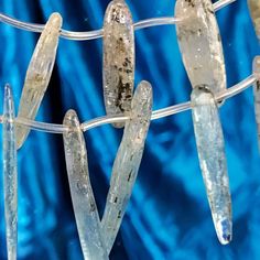 ice crystals are hanging on a clothesline with blue fabric in the backround