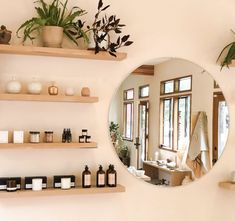 a mirror sitting on top of a wall next to shelves filled with bottles and plants