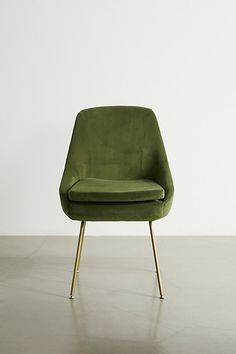 a green chair sitting on top of a hard wood floor next to a white wall