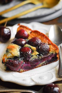 a piece of pie on a plate with cherries next to it and a fork